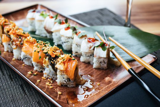 A plate of two sushi rolls with chopsticks - Powered by Adobe
