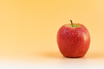 Fuji Apple with water drops isolated on yellow background