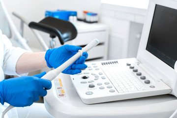 gynecologist doctor prepares an ultrasound machine for the diagnosis of the patient. Applies gel to a transvaginal ultrasound scanner. Women's Health Concept