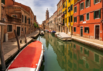 picturesque view at berth in a Venice chanel with boats, nice old builginds behind , church and beautiful sky on the background of the landscape