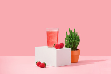 Glass of strawberry juice on red background.