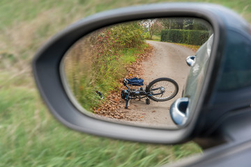 Unfall zwischen einem Auto und einem Fahrradfahrer dargestellt mit Fahrrad im Rückspiegel