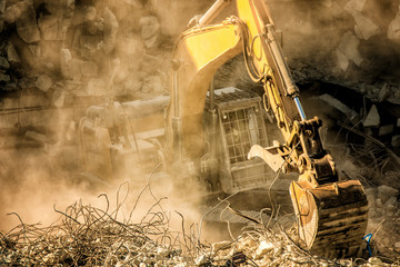 Heavy machinery surrounded with dust  cloud taking down an old building 