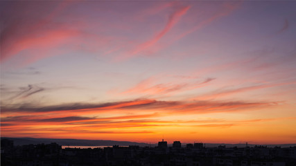 Obraz premium Beautiful sunset afterglow over a city. Vivid sky of golden and orange colors during sundown. Scenic skyscape at the sunset.
