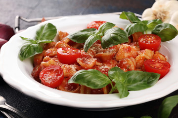 Pasta orecchiette. Plate of delicious orecchiette with tomato sauce garnished with parmesan cheese and basil on rustic background