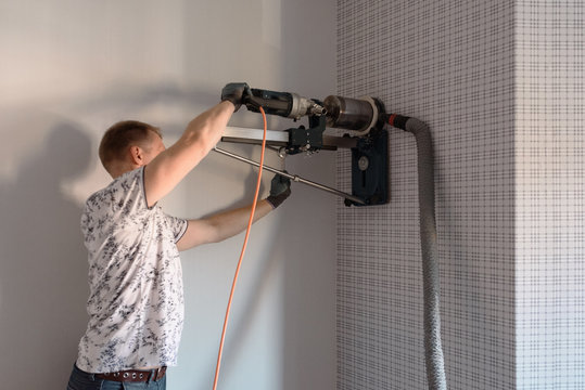 Laboring man drilling hole with contemporary equipment