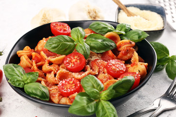 Pasta orecchiette. Plate of delicious orecchiette with tomato sauce garnished with parmesan cheese and basil on rustic background