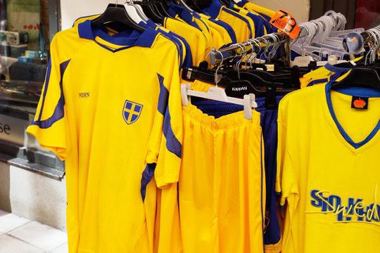 Stockholm, Sweden - July 12, 2018: Yellow souvenir football team suporter shirts with Swedish flags for sale at the Drottninggatan street in the downtown district.