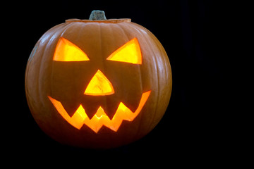 Illuminated Halloween Carved Pumpkin on a Black Background