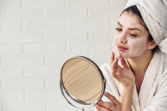 Young woman applying face mask at home. Natural Skin Care Routine. Cleaning face with natural cosmetics.