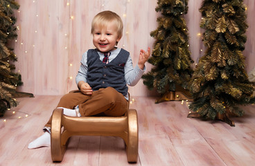 a boy near the Christmas trees on a sled, Christmas lights, rejoices and smiles, plays. holiday and vacation
