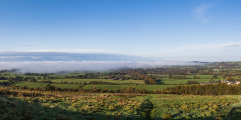 Obraz premium Fog and mist roll over the land below Beacon Fell Country Park seen on a cold October morning in 2019.