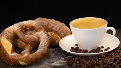 Breakfast with croissants, leaves, cutting board and black coffee on the morning breakfast.