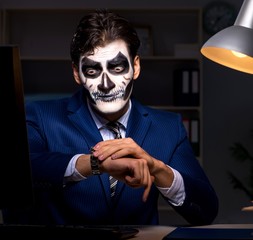 Businessman with scary face mask working late in office