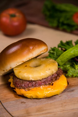 Hawaiian burger with salad and tomato on a wooden table