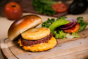 Hawaiian burger with salad and tomato on a wooden table