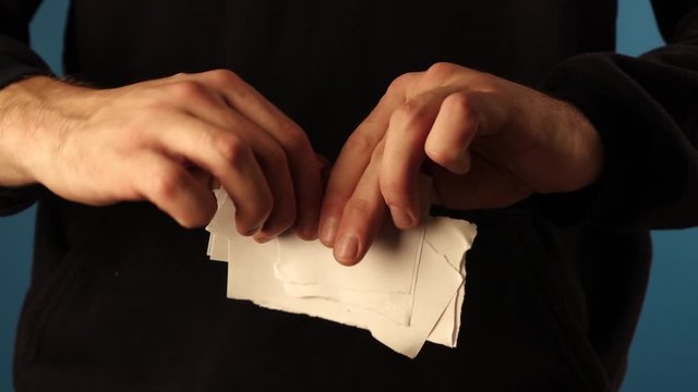 the man tears the paper apart and throws it down