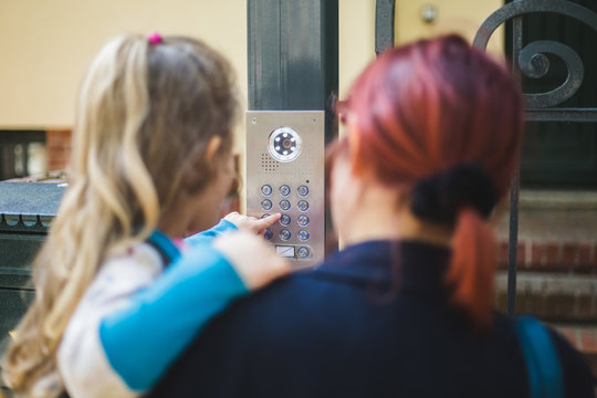 Close-up of mother carrying daughter typing password over security system on gate