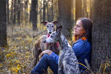 Woman resting with her dogs in forest at autumn