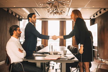Male and female lawyers shaking hands in board room at office