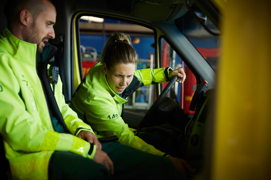 Paramedics discussing while sitting in ambulance in parking lot