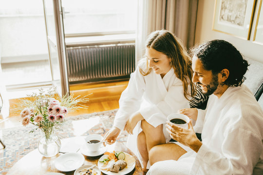 High angle view of couple in bathrobes enjoying breakfast at hotel room