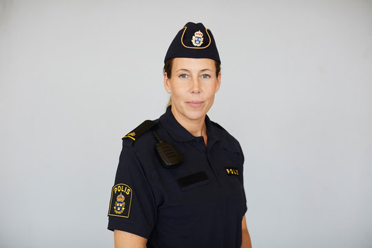 Portrait of policewoman in uniform standing against white background