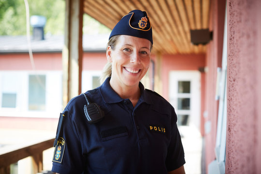 Portrait of smiling policewoman wearing cap standing in balcony at police station