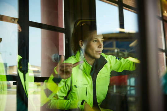 Female paramedic listening to coworker seen through ambulance windshield