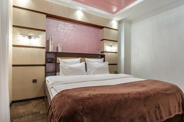 Interior of the modern luxure bedroom in studio apartments in brown and pink light color style