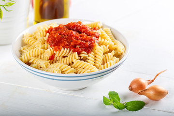 Pasta with tomato sauce on wooden background.