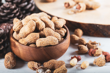 Peanuts in the shell and peeled close up in a wooden cup. Background with peanuts.