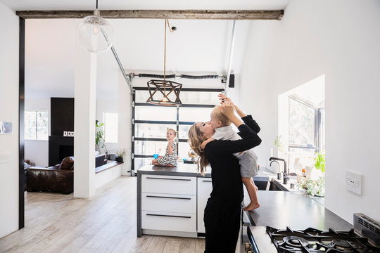 Mother holding son on kitchen counter