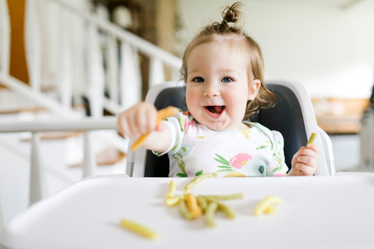 Baby girl eating in high chair
