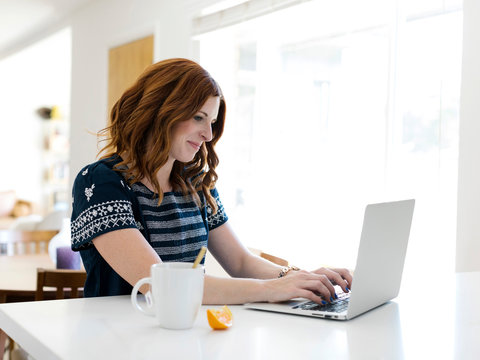 Woman using laptop at dining table