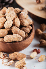 Peanuts in the shell and peeled close up in a wooden cup. Background with peanuts.
