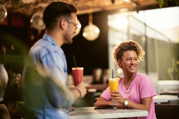 Happy woman drinking fruit cocktail with the boyfriend in a cafe.