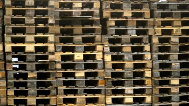 Close up of stacked wooden pallets on a storage place. Pan right to left