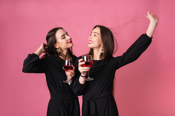 Two women celebrate the New Year party having fun laughing and drinking wine.