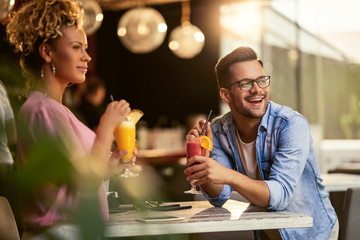 Young happy couple enjoying in cocktails while relaxing in a bar.