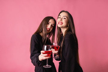 Two women celebrate the New Year party having fun laughing and drinking wine.