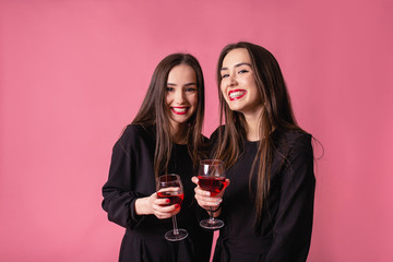 Two women celebrate the New Year party having fun laughing and drinking wine.