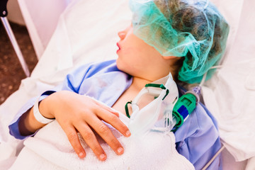 Child in a hospital resting after an intervention asleep by anesthesia,  unfocused background.