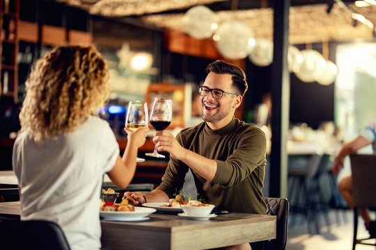 Cheerful couple toasting with wine during lunch time in a restaurant.