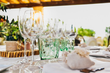 Empty glasses next to the cutlery and table linen of a guest table.