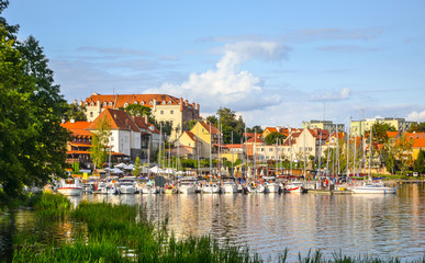 View of the center of Ryn, the castle, the lake and the marina with moored boats. Masuria, Poland. - obrazy, fototapety, plakaty