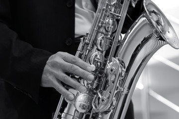 A man in a strict dark suit plays the saxophone