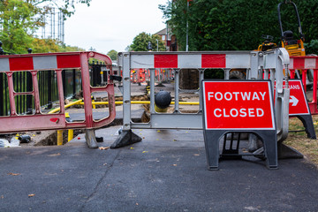 Roadworks in urban residential area with Footway closed red sign and barricades blocking way