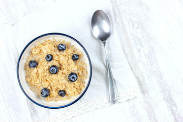 Oatmeal with fresh blueberries. Diet food - oatmeal porridge in a plate with a spoon.