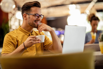 Happy freelancer using laptop while relaxing in a cafe.